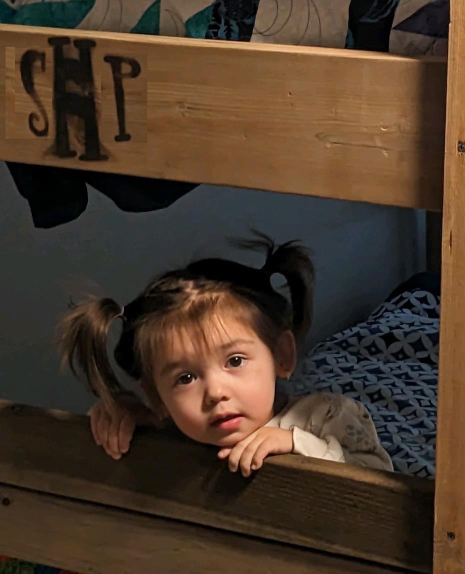 A little girl on a bunkbed.