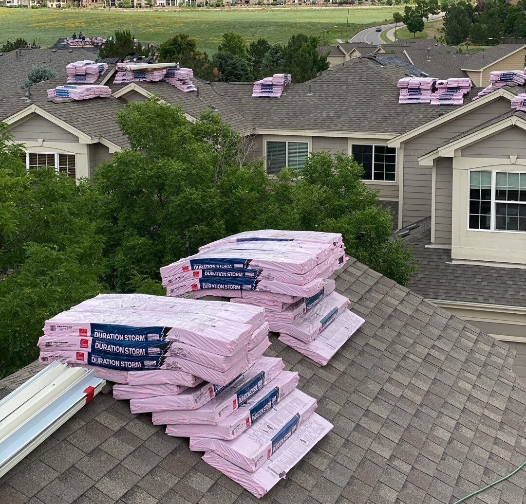 Packs of Owens Corning insulation shingles are stacked on the roof of a residential home in preparation for roofing work.