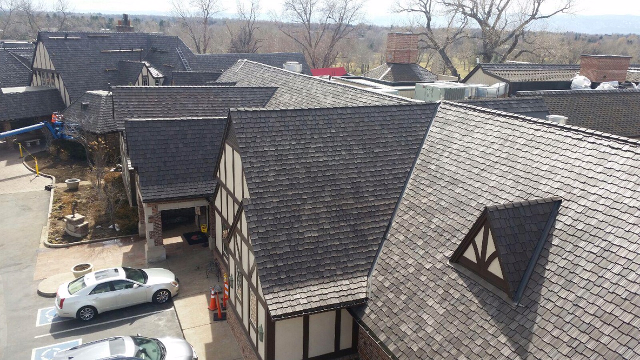 Elevated view of a Tudor-style complex with distinctive timber framing and multiple gabled roofs, with a police car parked below.