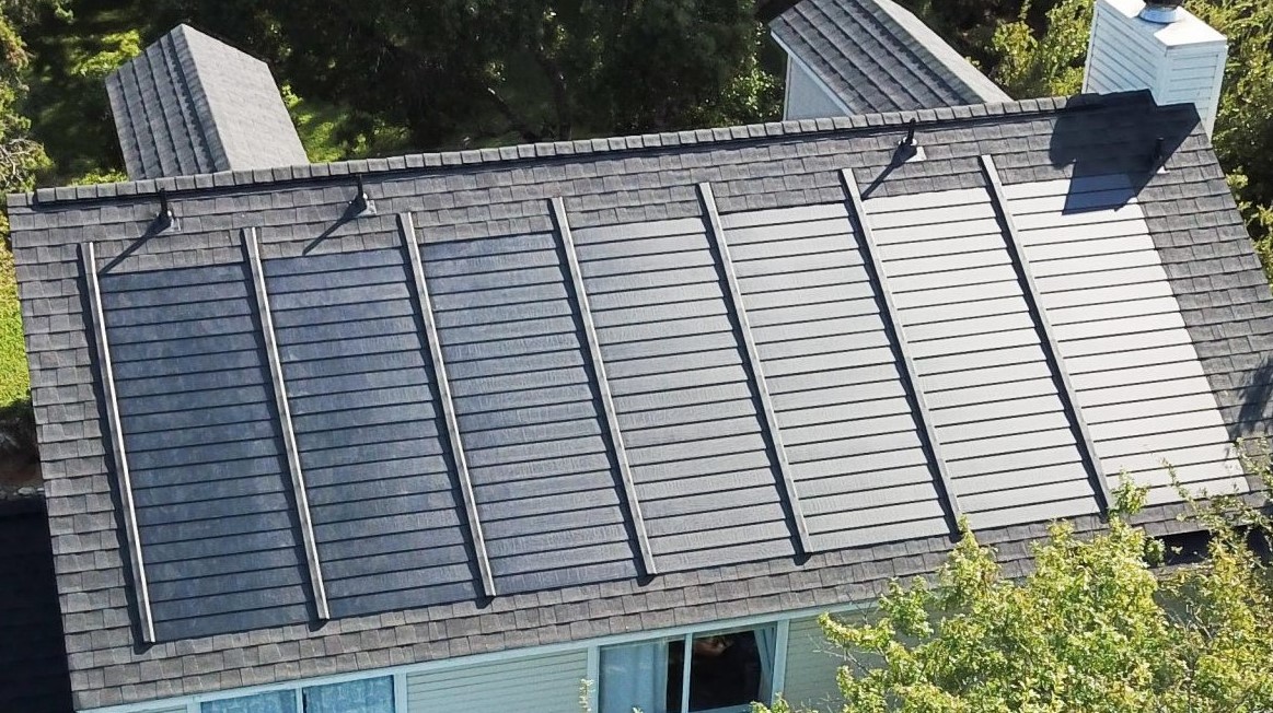 Aerial view of a residential roof with solar panels.