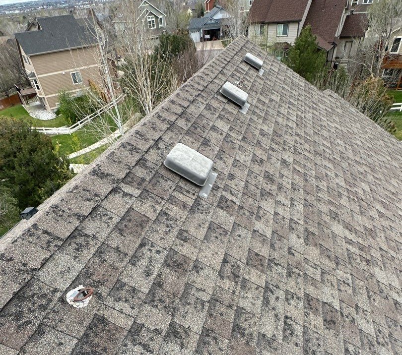 Aerial view of a house's shingled roof with vent covers.