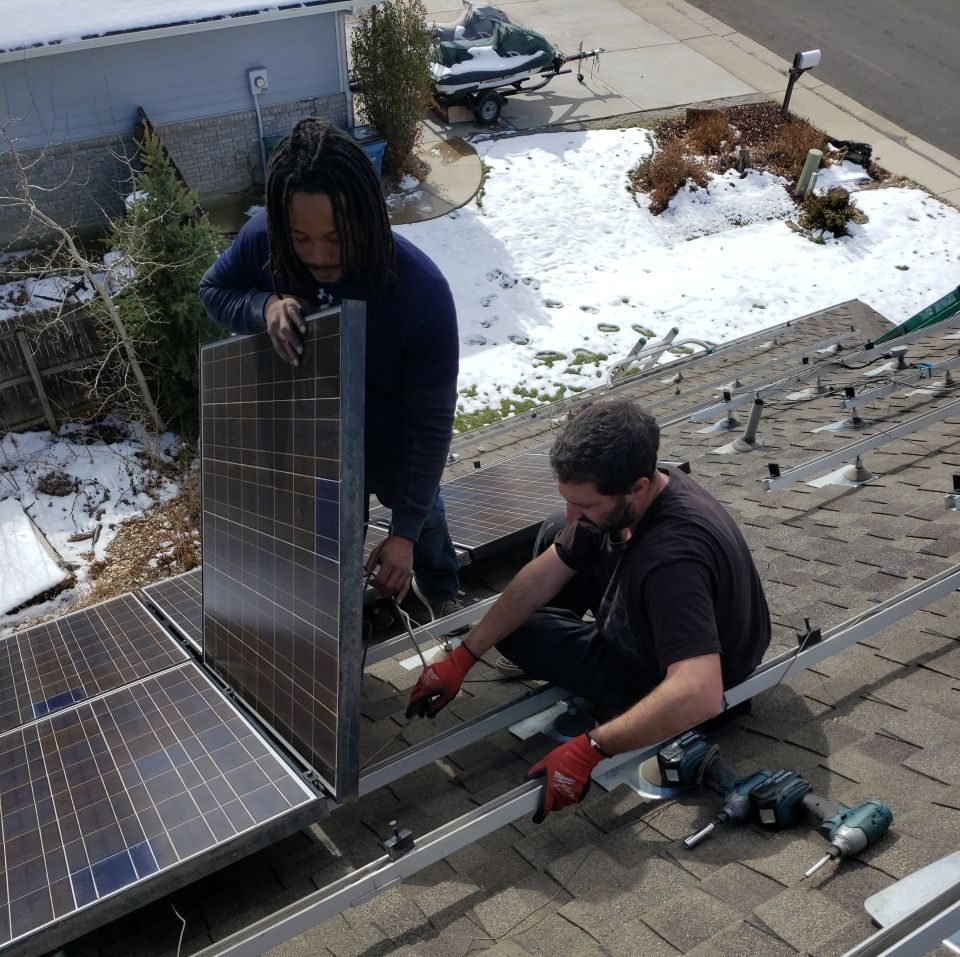 Technicians installing solar panels on a house roof in winter.