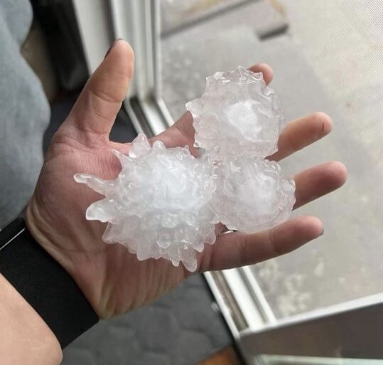 A person holding large chunks of hail