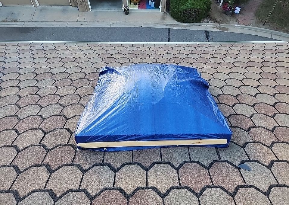Tarp-covered object on patterned pavement, suggesting a temporary fix or protection.