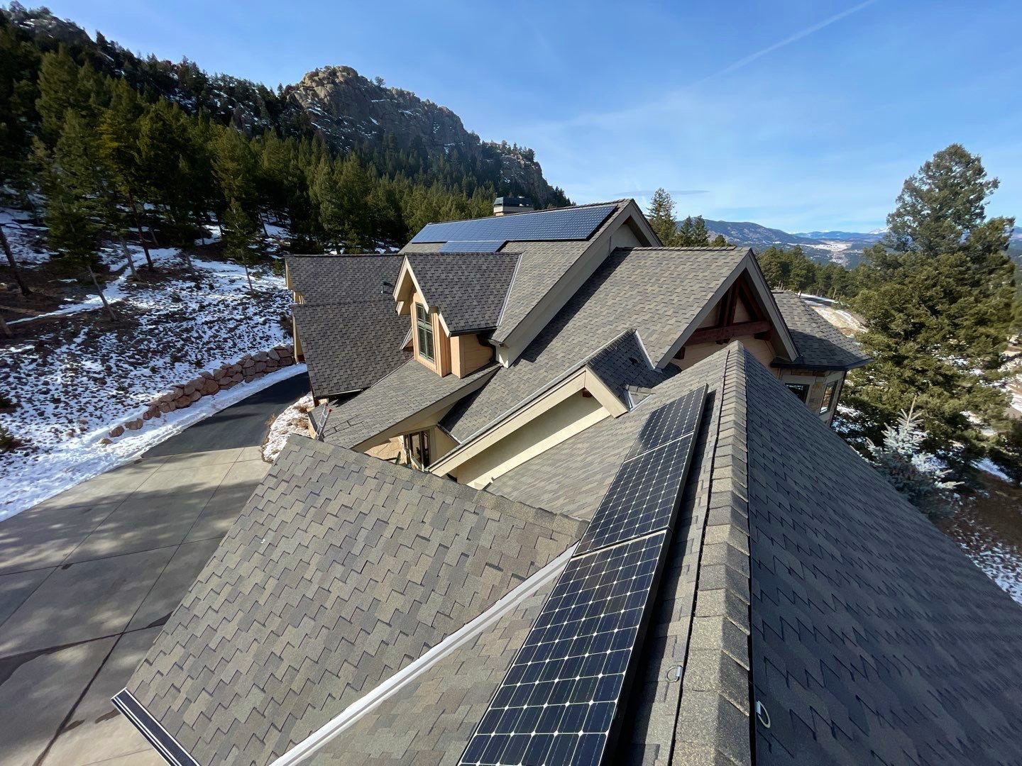 Mountain home with solar panels on roof during winter.