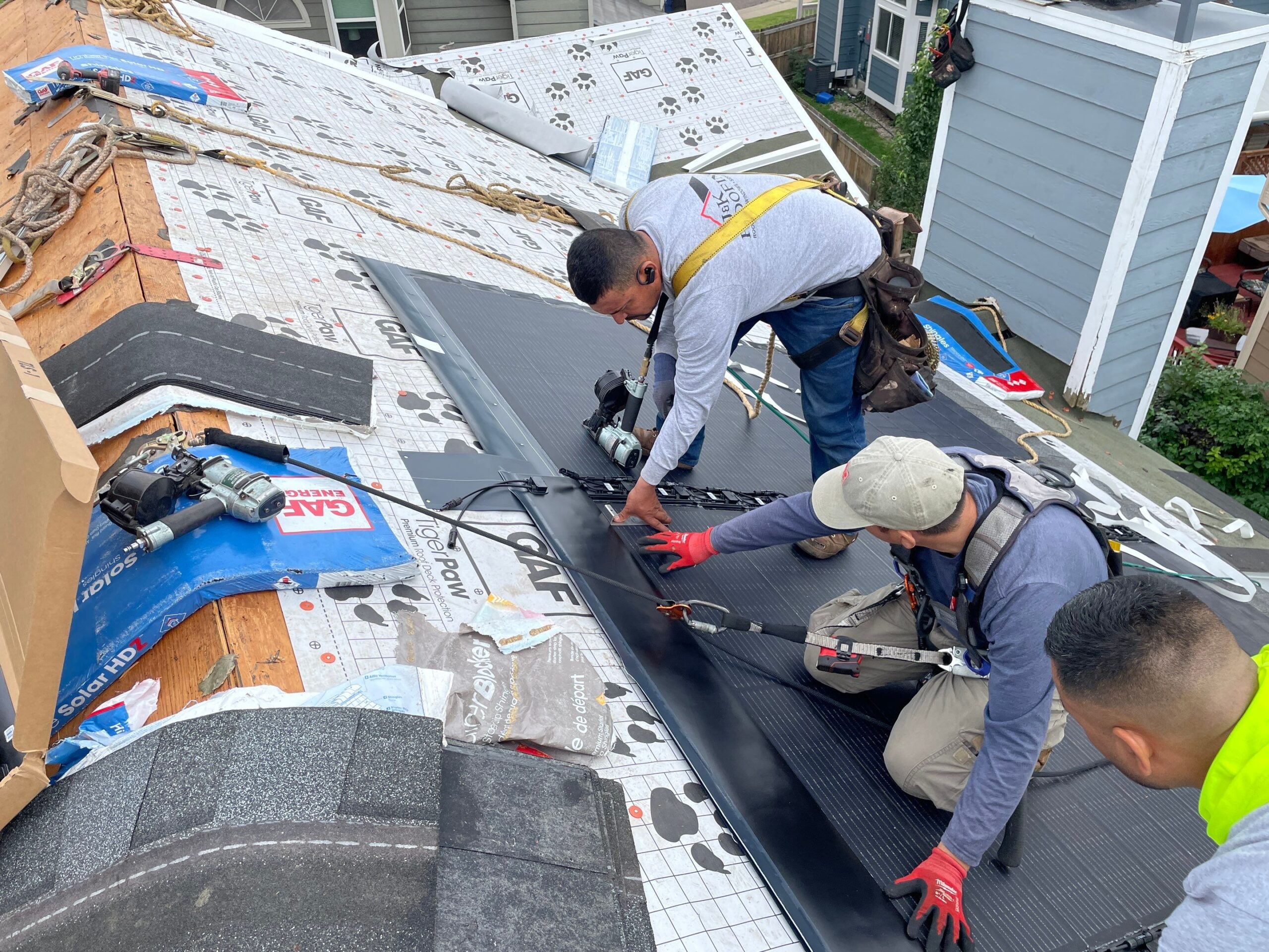Workers installing solar roofing on a residential home.