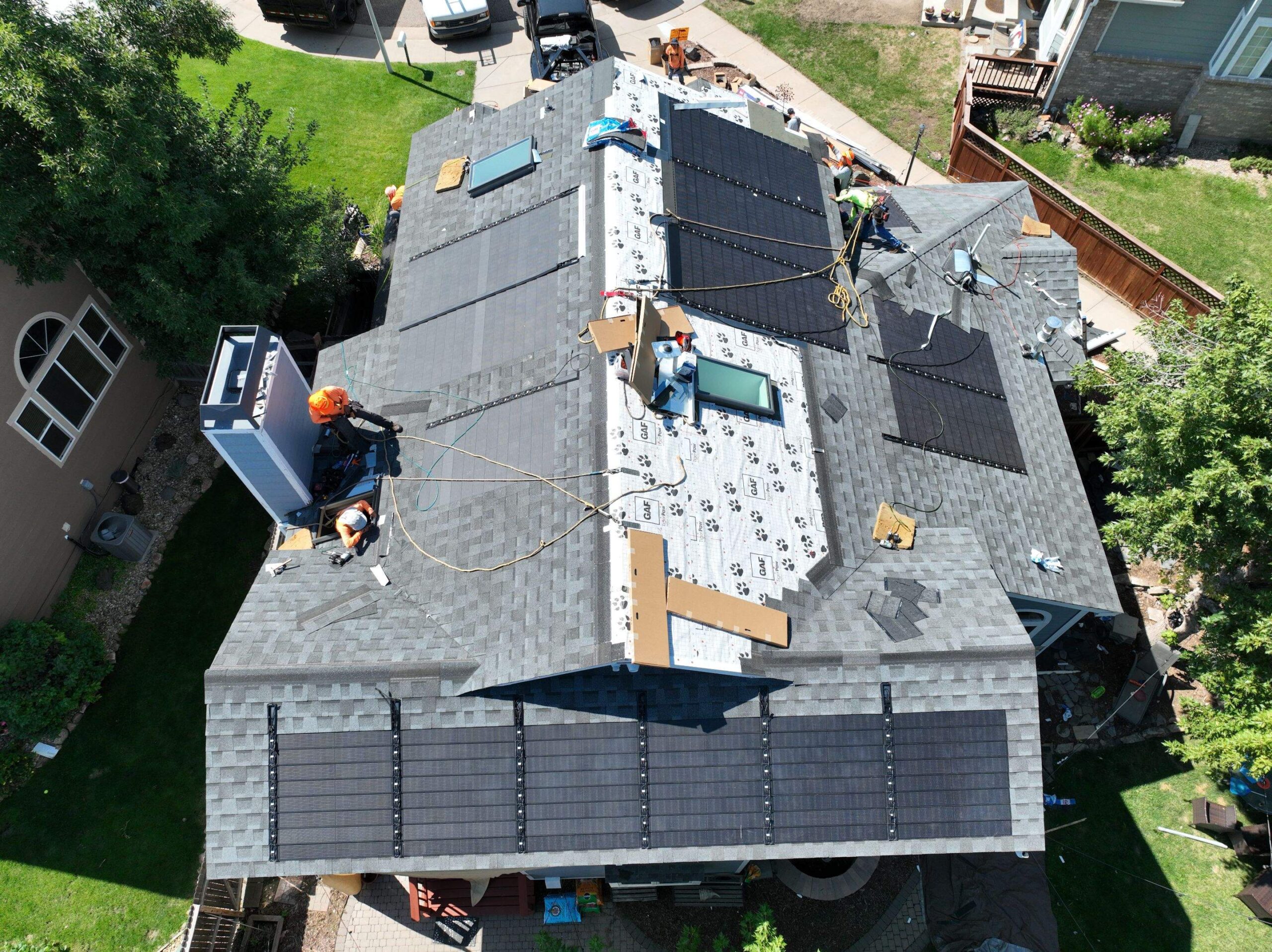 Aerial view of a house roof under construction with solar panels installed.