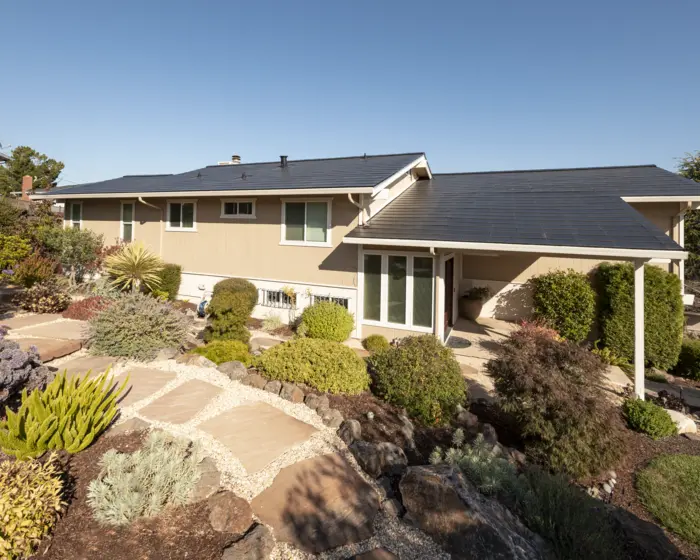 Suburban home with solar panels on the roof and landscaped garden.