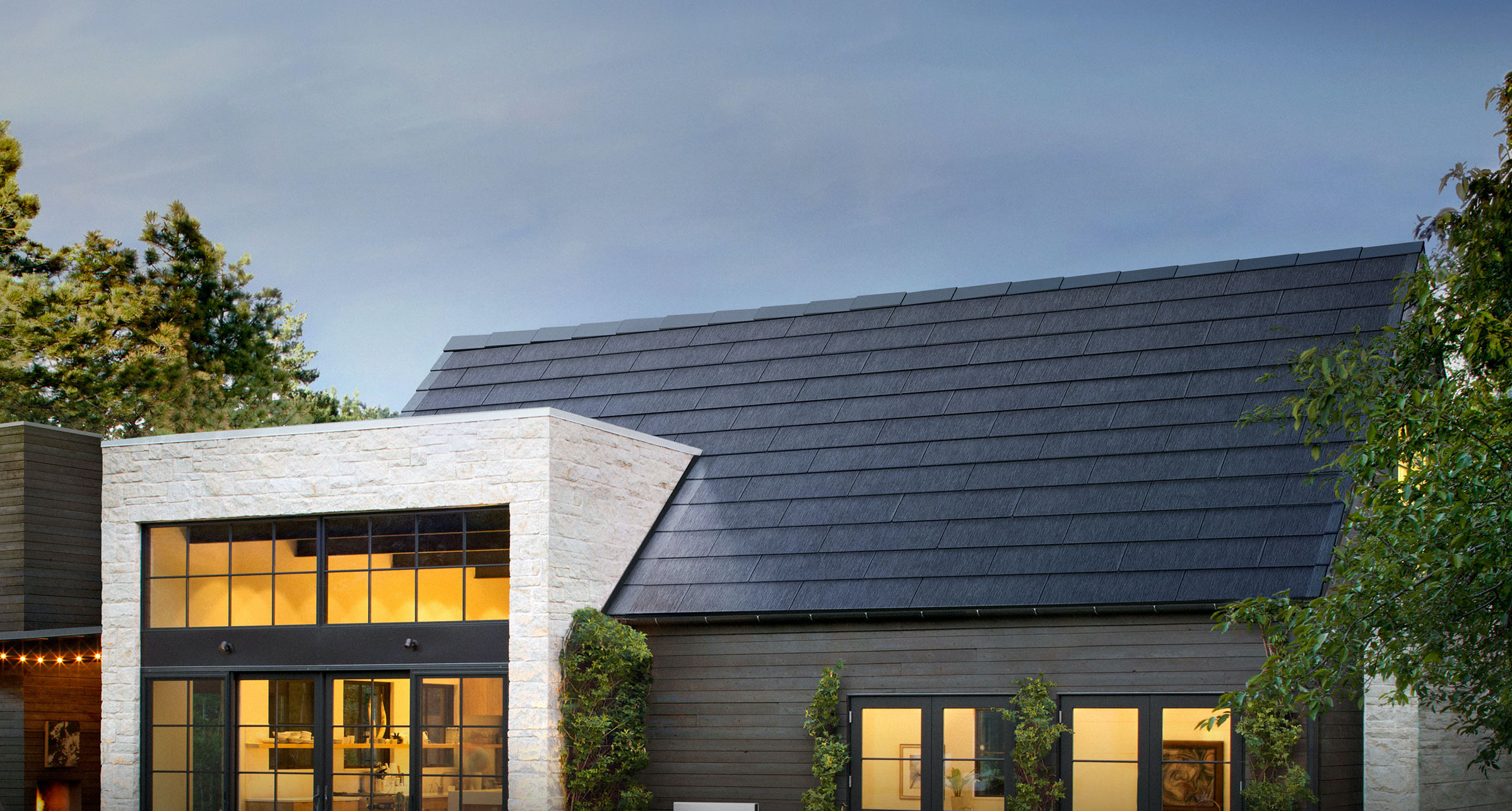 Contemporary home with Tesla solar roof tiles under a twilight sky.