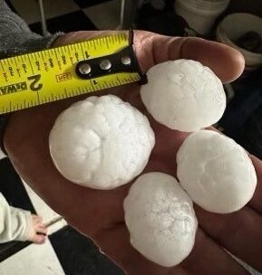 Hail stones with a measuring tape showing the size.