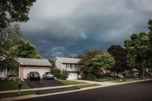 Thunderstorm clouds over a suburban neighborhood in Denver with a house with a roof leak