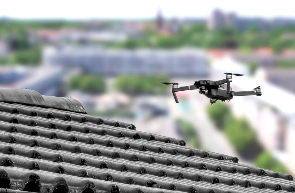 Drone in the air inspecting the roof over the house. Close-up of drone and roof.