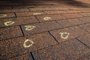 Insurance Adjuster marked hail damage on a insureds roof. hail damange and insurance